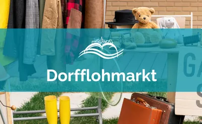 Dorfflohmarkt – Kleiderstange, Teddybär und Koffer an einem Verkaufsstand