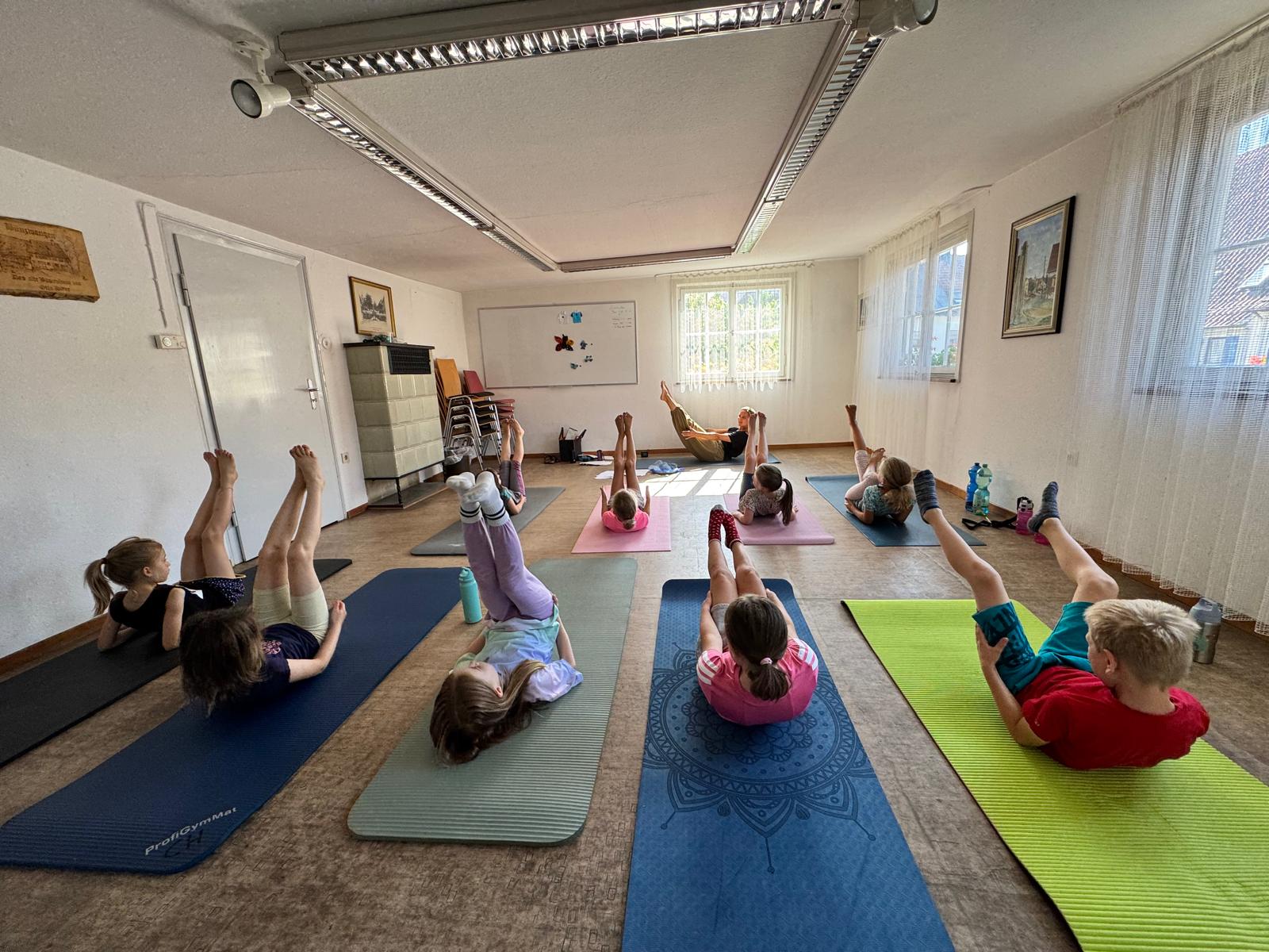 Kinder machen Übungen auf Yogamatten in einem Gymnastikraum