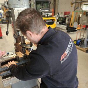 Mitarbeiter der AS-Service GmbH bearbeitet ein Kupplungsteil an der Ständerbohrmaschine